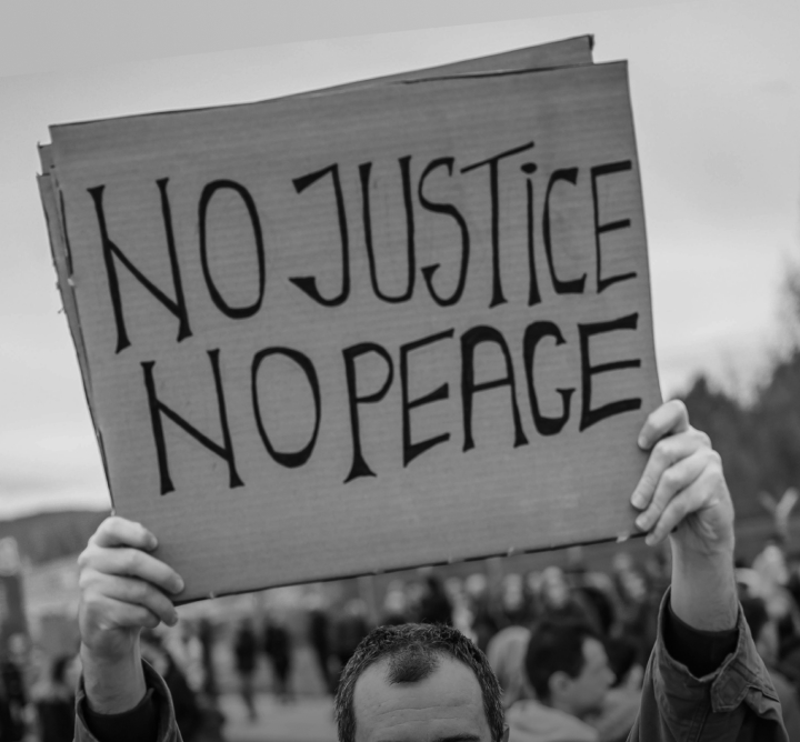 Hands holding a sign that reads "NO JUSTICE NO PEACE"